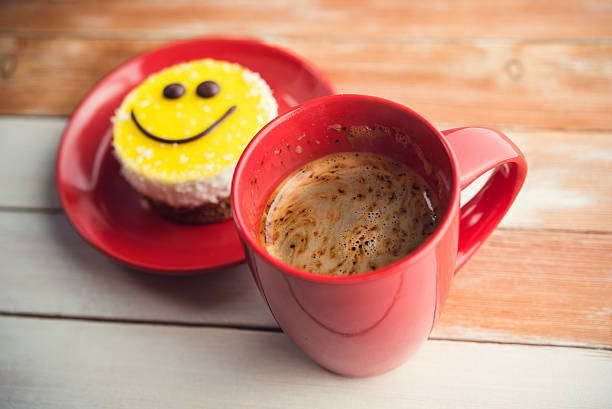 istock Coffee red cup and smile cake on wood table 499922568