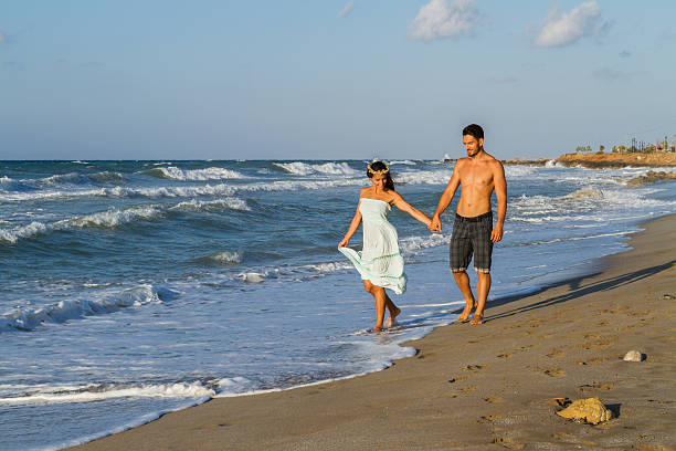 istock Young couple enjoys walking on a hazy beach at dusk 499927516