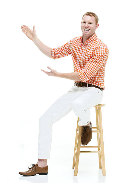 istock Cheerful casual man on stool and presenting 499930952