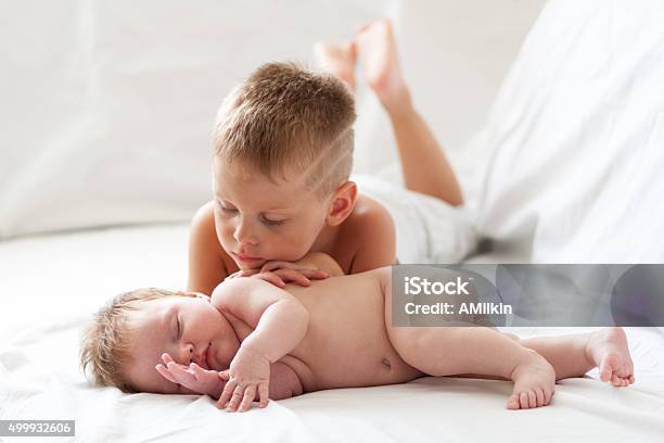 Little Boy Watching His Newborn Sister Indoors Stock Photo - Download Image Now - 0-11 Months, 2-3 Years, Baby - Human Age