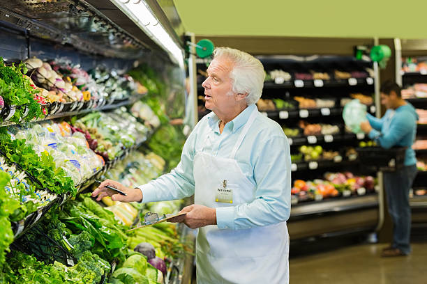 пожилой человек, принимая запасов, работая в супермаркет продуктов раздел - smart casual occupation casual healthy eating стоковые фото и изображения
