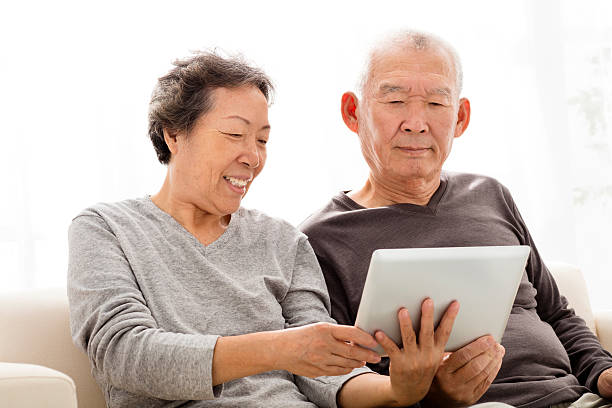 istock happy Senior Couple watching the tablet on sofa 499957156