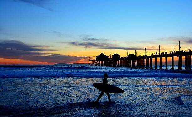 surfer silhouette in der dämmerung - orange county california beach stock-fotos und bilder