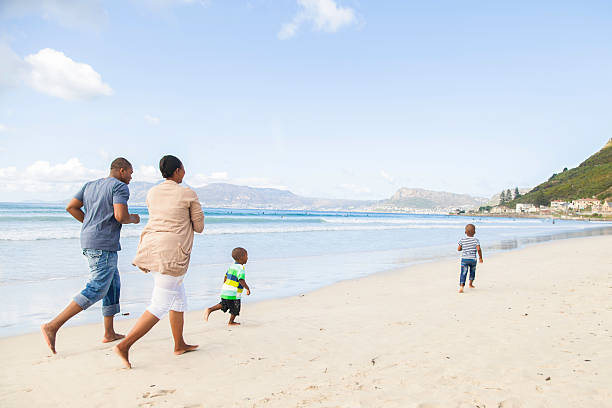 istock African family running on the beach while son runs ahead 499980467