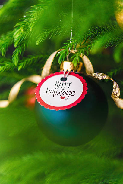 istock Christmas bauble with Happy Holidays message on Christmas tree branches 499980692