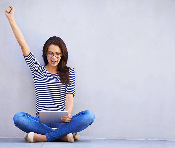 One hundred likes! Full length shot or a young woman sitting cross legged using a digital tablethttp://195.154.178.81/DATA/i_collage/pi/shoots/783649.jpg real symbol stock pictures, royalty-free photos & images