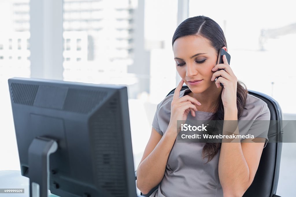 Pensive attractive businesswoman having a phone conversation Pensive attractive businesswoman having a phone conversation in her office 20-29 Years Stock Photo