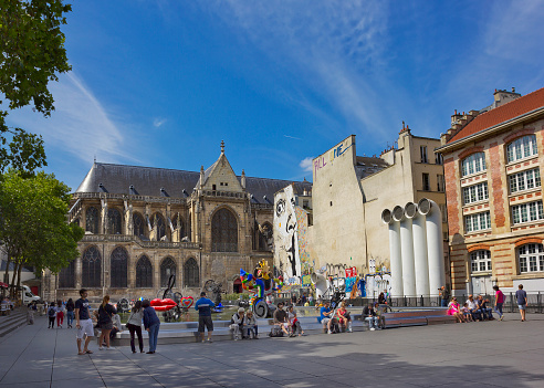 Paris, France - July 31, 2015: Modern Stravinsky Fountain and ancient gothic Church of Saint-Merri with resting people