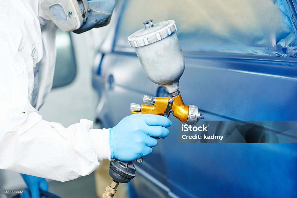 painting auto car automobile repairman painter hand in protective glove with airbrush pulverizer painting car body in paint chamber Paint Stock Photo