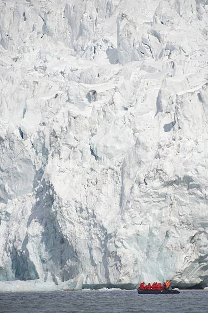 istock Red-coated photographers in Zodiac before ice cliff 500003627