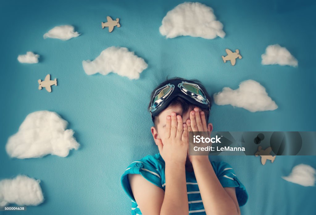 boy lying on blanket with white clouds boy lying on blanket with white clouds in pilot glasses Child Stock Photo