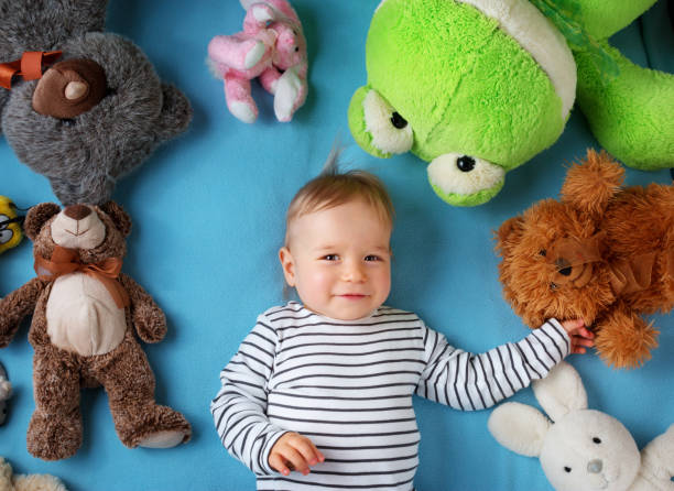 istock Happy one year old boy lying with many plush toys 500004678