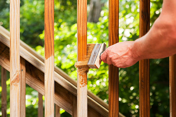 istock Hand with Paintbrush Staining Wood Deck Railing 500004791