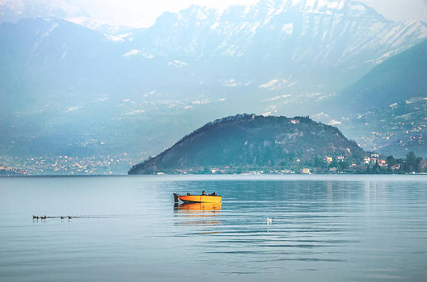 Iseo, Italy - February 16, 2013: A yellow boat navigate in the waters of Iseo lake during winter morning, on background the Monte Isola promontory and mountains
