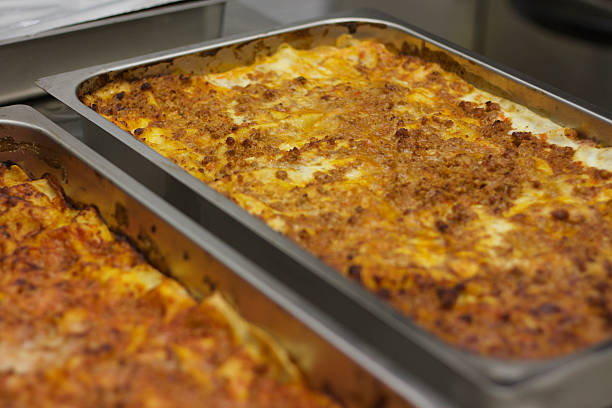 Lasagna: Two Huge Pans of Traditional Baked Lasagna (Close-Up) Lasagna: two huge rectangular stainless-steel pans of traditional meat-based baked lasagna (close-up), ready to cut and serve. large pasta pot stock pictures, royalty-free photos & images