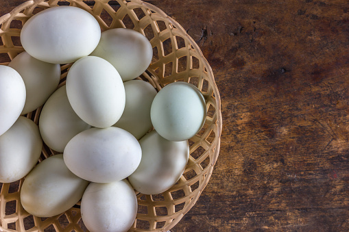 white eggs in the plastic basket on the old wooden table back round