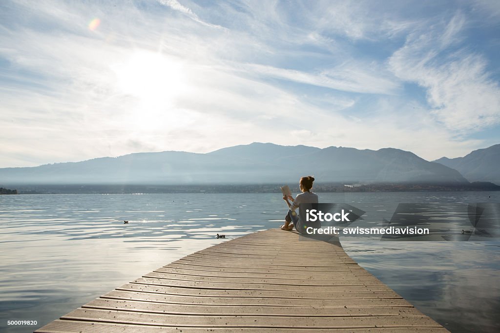 Femme se détend sur le lac pier, lire un livre - Photo de Lire libre de droits