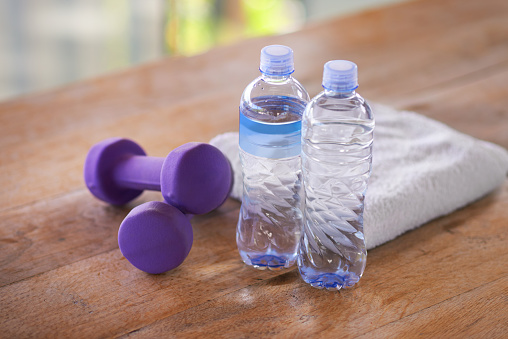 A shot of dumbells, water bottles and a towel on a wooden tablehttp://195.154.178.81/DATA/i_collage/pi/shoots/783594.jpg