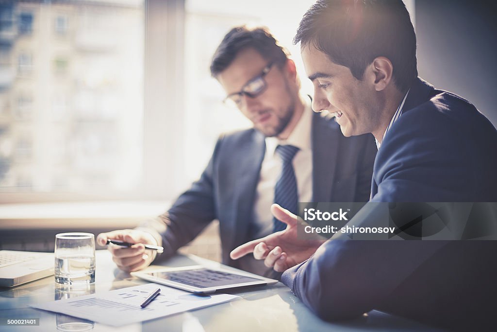 Discussing project Image of two young businessmen using touchpad at meeting Business Meeting Stock Photo
