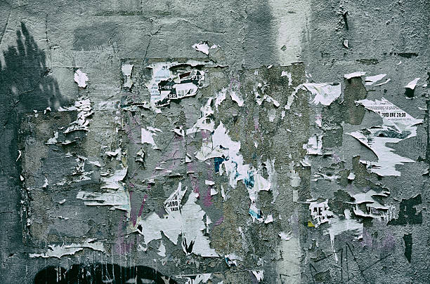 Pieces of torn paper peeling off wall used as billboard Rough gray wall used as billboard and only small remains of the message remains as paper peeling off the wall peeled stock pictures, royalty-free photos & images