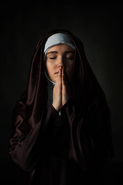 Catholic nun Young catholic nun with pray. Photo on black background. nun catholicism sister praying stock pictures, royalty-free photos & images