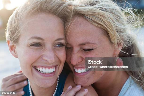 Dos Mujeres Siéntese En La Playa Hablando Y Riendo Foto de stock y más banco de imágenes de Hermana - Hermana, Adulto, Actividades recreativas
