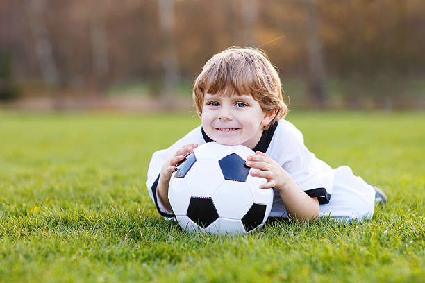 небольшой веер мальчик на общественный просмотр футбол или футбол - playing field goalie soccer player little boys стоковые фото и изображения