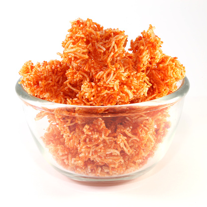 Sweet crispy noodles in a glass blow on white background