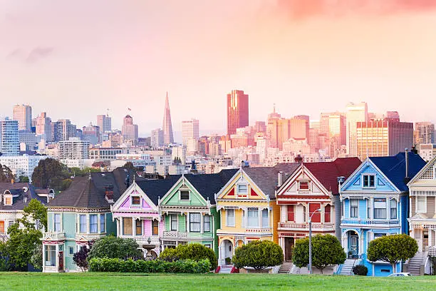 Early evening warm light skyline of San Francisco and painted ladies from Alamo park square 