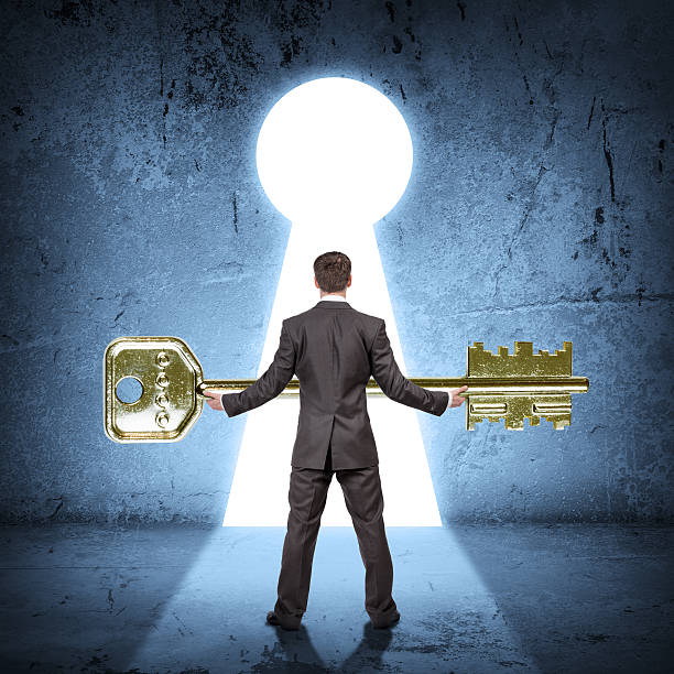 istock Man holding huge gold key, rear view 500057360