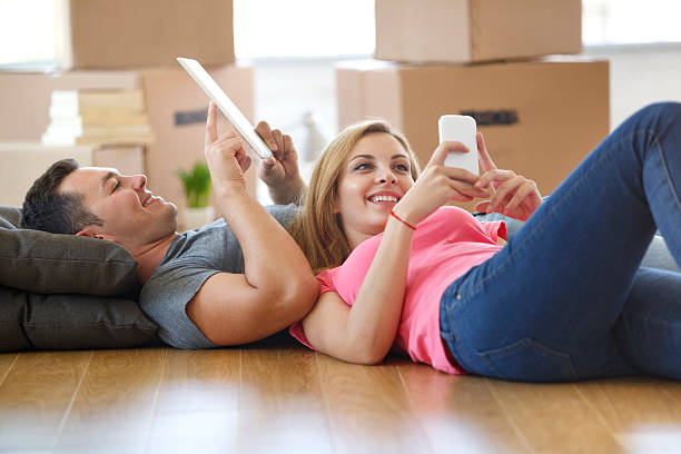 istock Young couple using mobile phone and tablet in new home 500059418