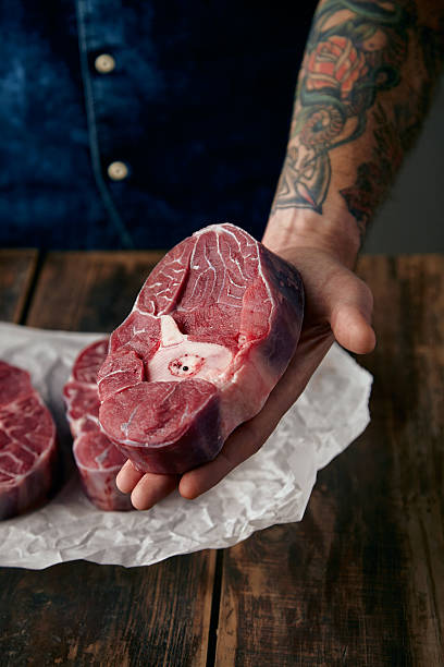istock Tattoed hand offers a piece meat stake above two steaks 500059814