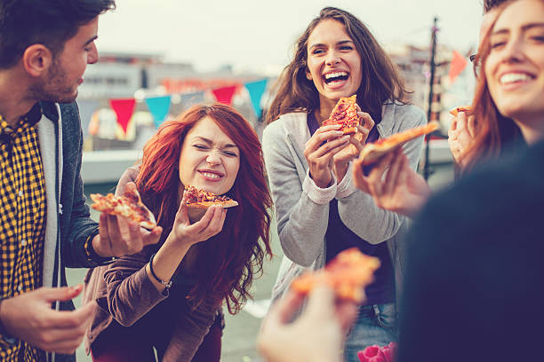 jóvenes de comer pizza en fiesta - pizza party fotografías e imágenes de stock
