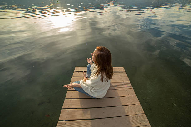 istock Woman exercises yoga on lake pier 500080614