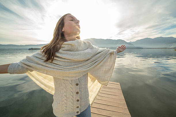 istock Young woman stands on pier arms outstretched, relaxes 500089332