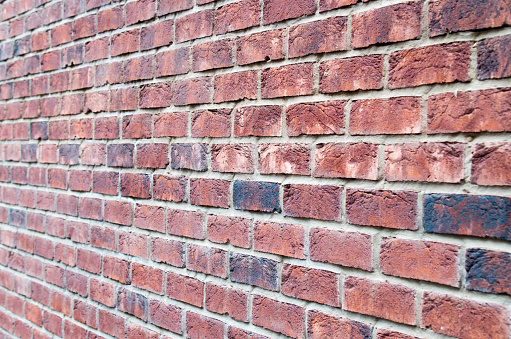 Fragment of brown brick wall with a shallow depth of field, which is photographed at an angle to the plane. Selective focus.