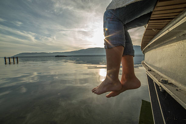 istock Woman's feet dangle from wooden wharf, above lake 500092506