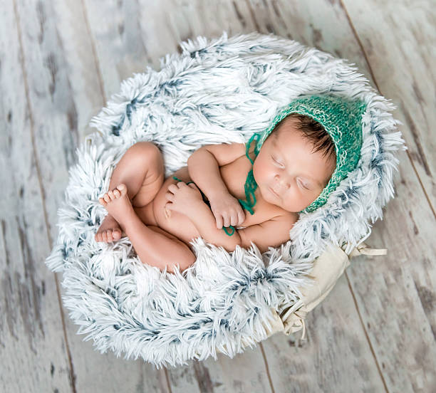 istock newborn baby with green hat sleeping in a basket 500094618