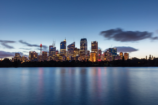 Illuminated Sydney Skyline Skyscrapers mirroring in the tranquil water at dusk. Panoramic view towards of the Sydney Downtown Skyline Skyscrapers, Tower and Office Buildings. Scenic Twilight  Sydney Panorama Long Time Exposure. Sydney, Australia. Canon 5DSR 50MPixel Panorama.