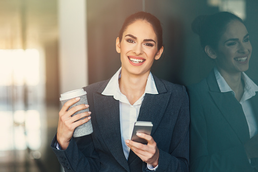 Modern portrait of a young professional business woman holding a tablet and coffee.