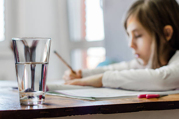 verre d'eau sur une table - schoolgirl little girls crayon human face photos et images de collection