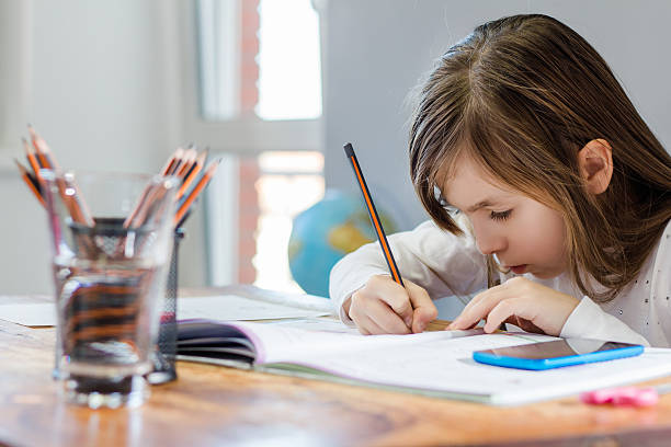 jeune fille à faire leurs devoirs - schoolgirl little girls crayon human face photos et images de collection