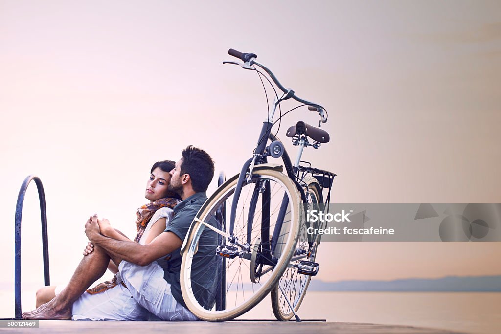 Couple in love resting on a boardwalk at lake Couple in love resting on a boardwalk with a bike at the lake Bicycle Stock Photo