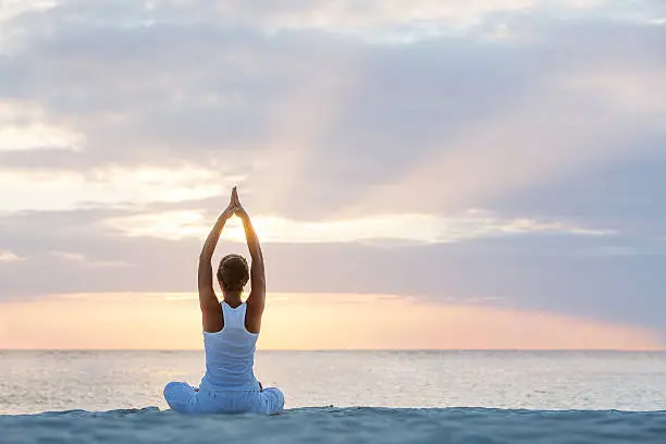 Caucasian woman practicing yoga at seashore