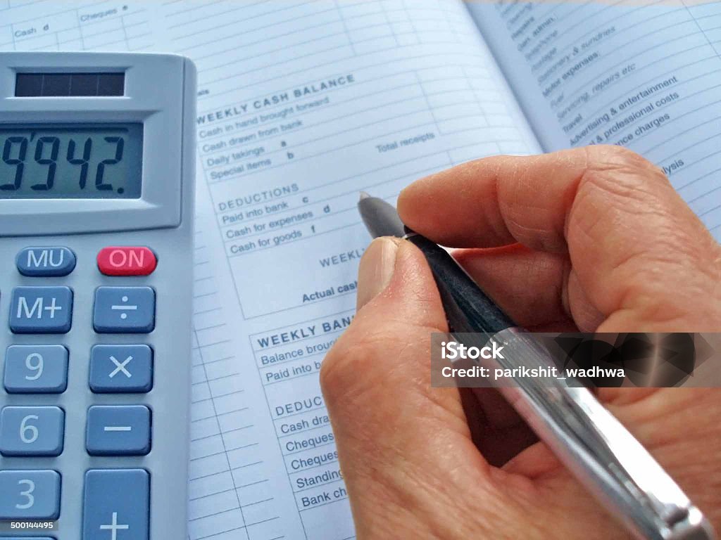 Business Accounts Hand with a pen over an accounts book Book Stock Photo