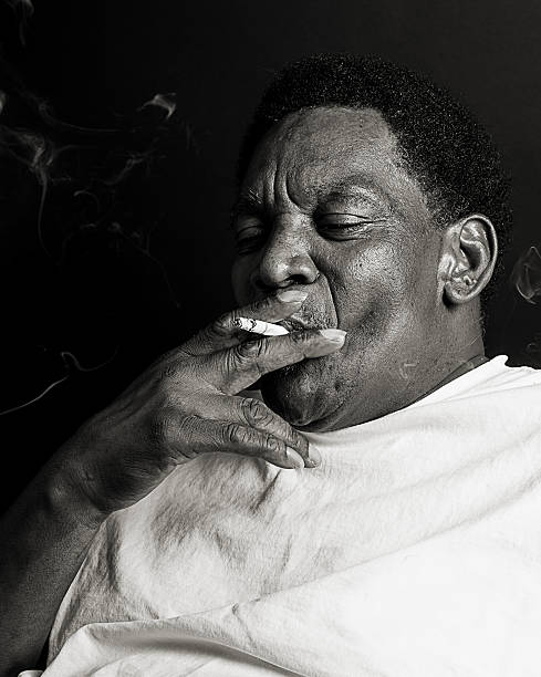 graves hombre afroamericano fumar un cigarrillo - portrait black and white senior men wisdom fotografías e imágenes de stock