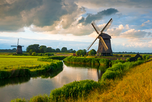 Windmill along a canal in dramatic evening light near Schermerhorn, Netherlands