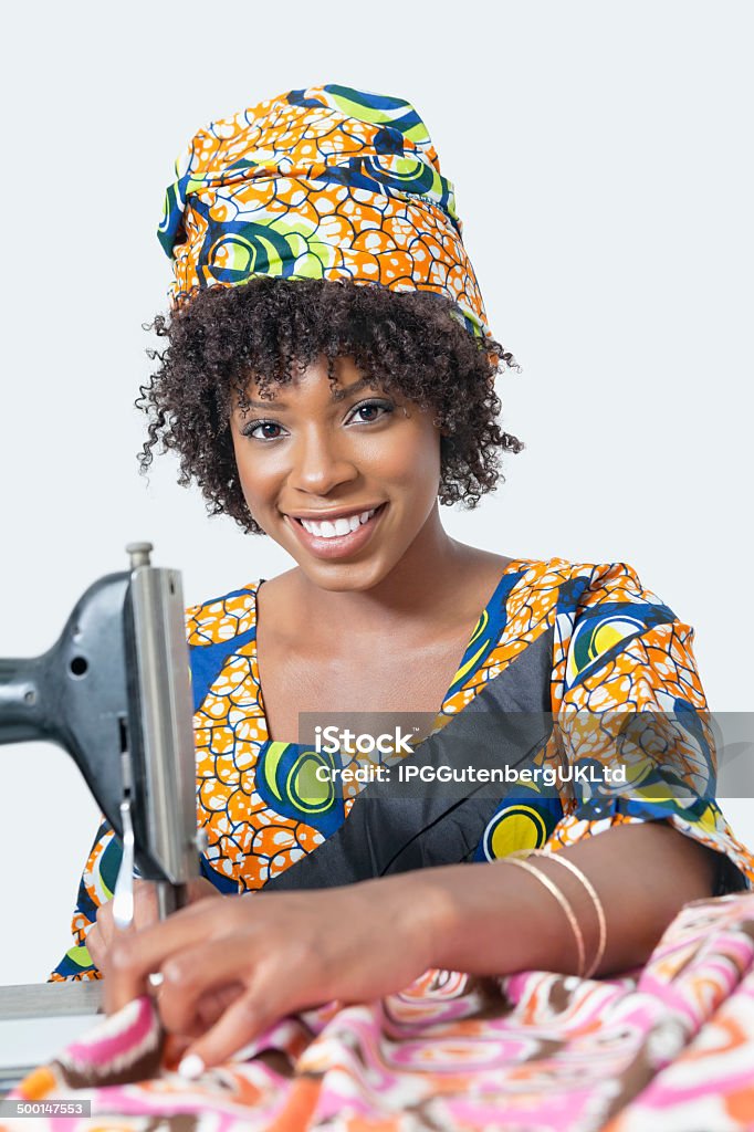 portrait of an African American woman Portrait of an African American woman using sewing machine over gray background 20-24 Years Stock Photo