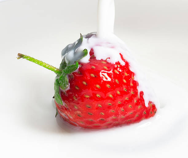 istock milk or cream poured on fresh red strawberry, close up 500149577