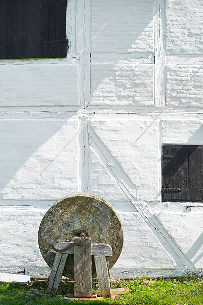 An old millstone in front of a wall.